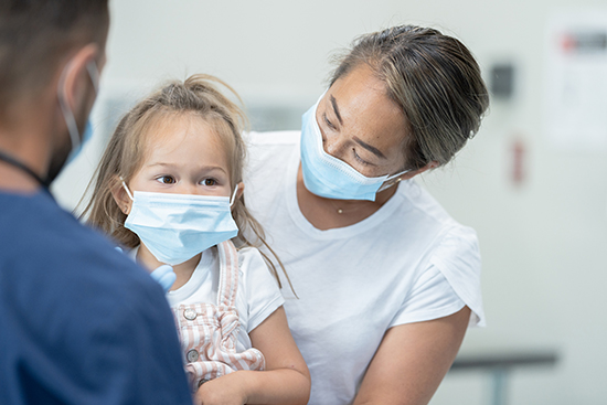 Mom and daughter wearing masks with doctor.